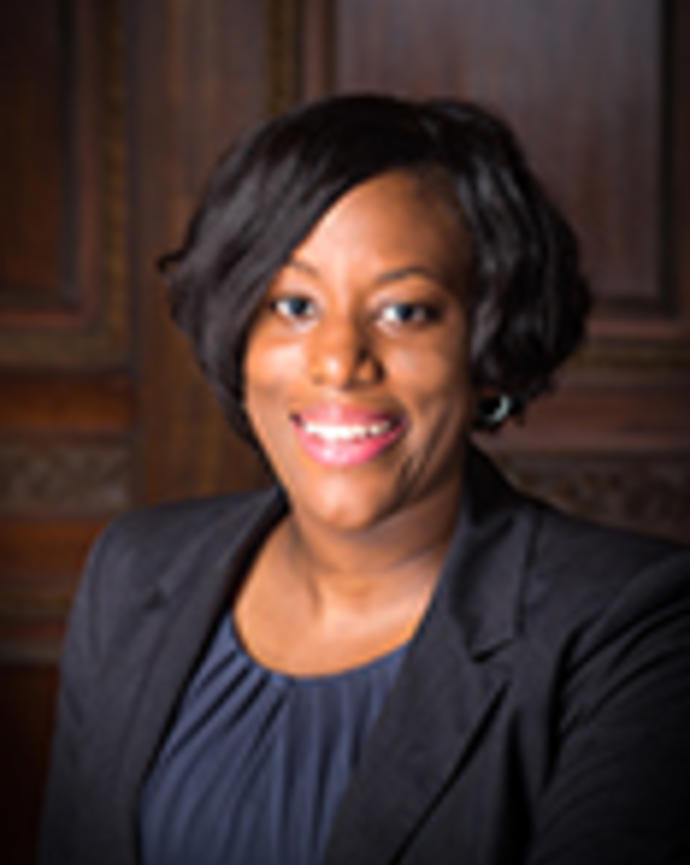 Marshala Lee has short black hair. She is wearing a dark blue blouse and black blazer.