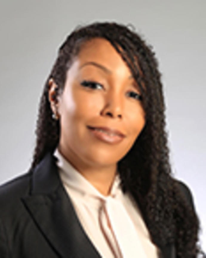 Shantel Magee has long twisted black hair. She is wearing a cream blouse and black blazer.