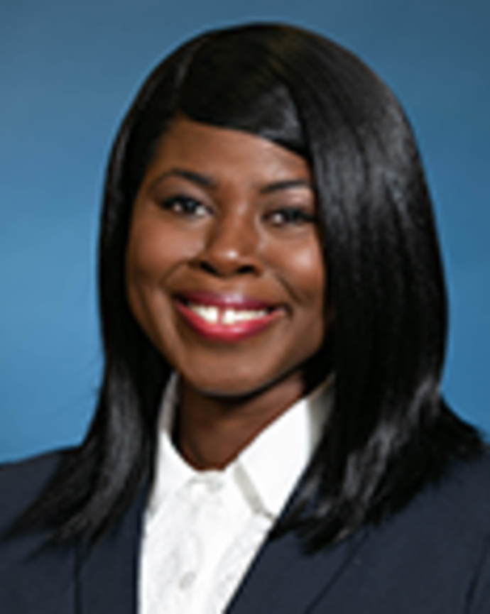 Jessica Pierre Francois has medium length straight black hair. She is wearing a white shirt and black blazer.