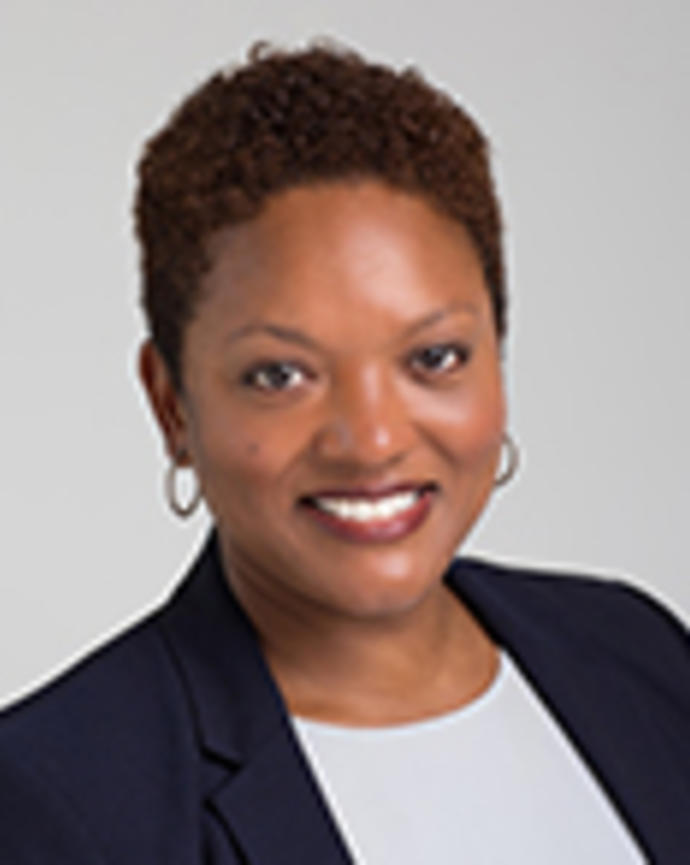 Michelle Taylor has short black hair. She is wearing a white shirt and black blazer.