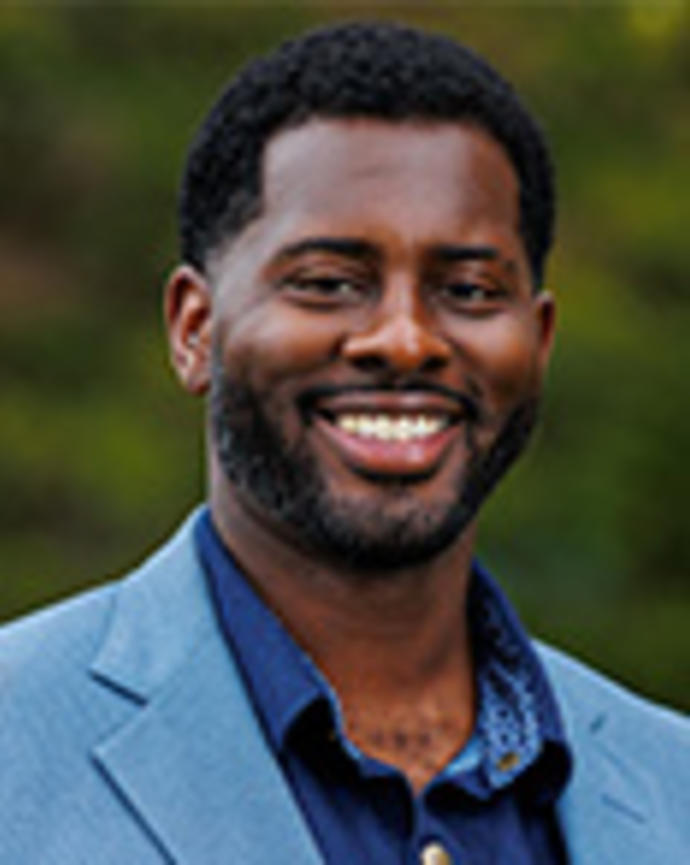 Yvorn Aswad is standing outside and wearing a blue shirt with a light blue blazer.