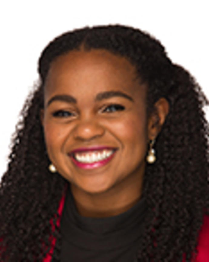 Yamicia Connor has long curly black hair. She is wearing a black blouse and red jacket.
