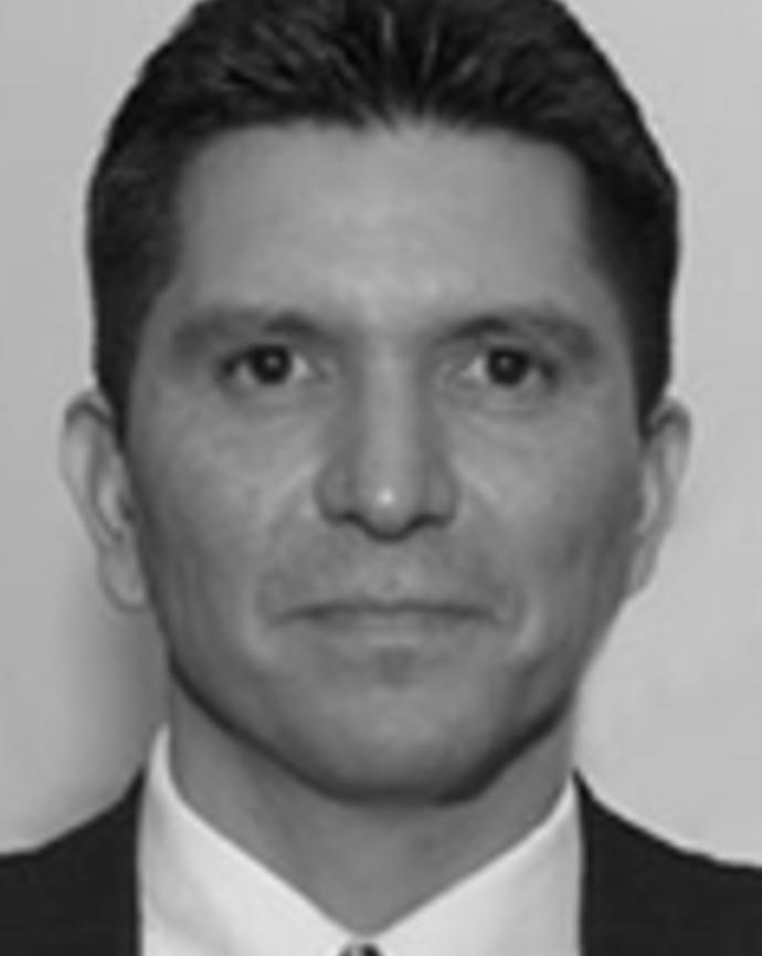 Philip DeChavez has short hair combed back and is wearing a suit.