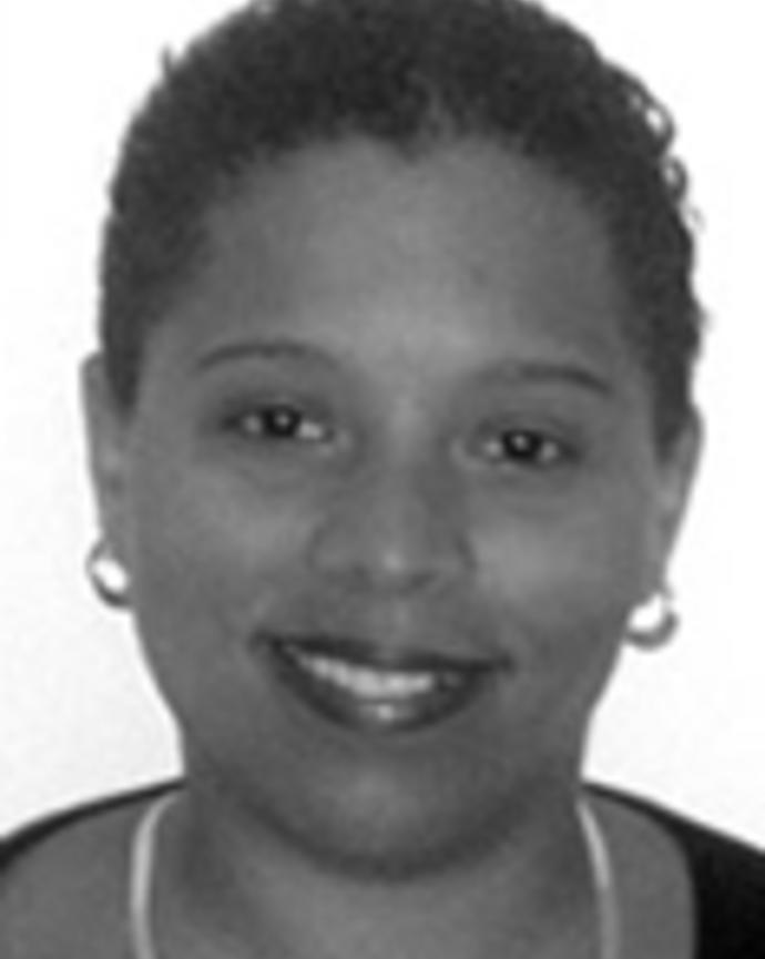 Nefertiti Durant has very short curly black hair. She is wearing earring and a necklace.