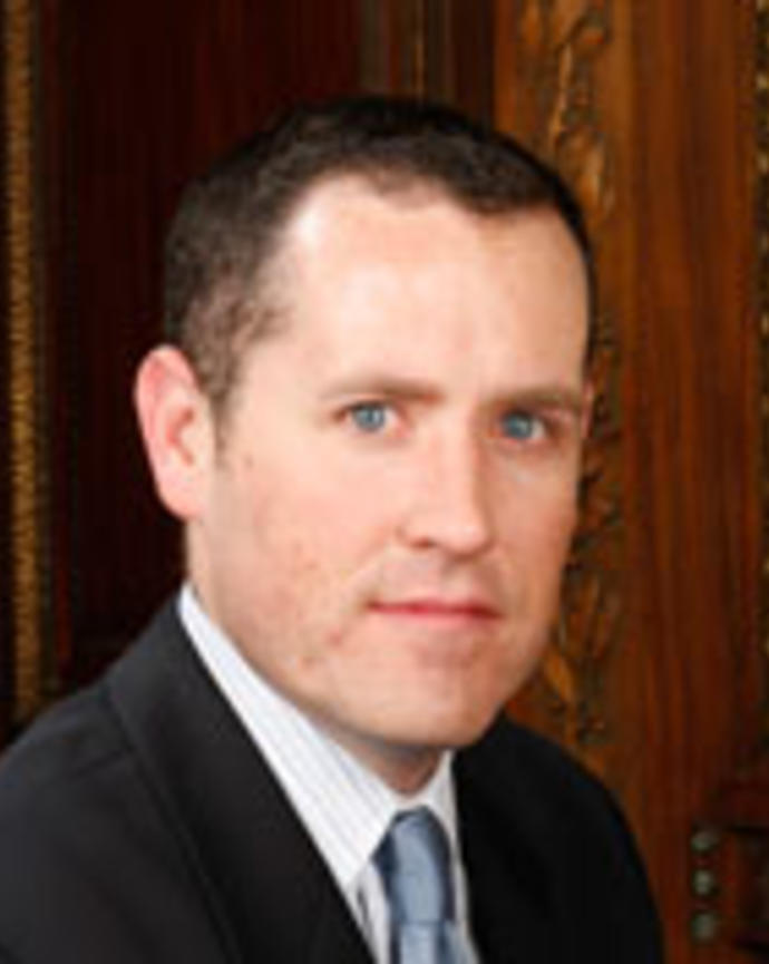 Thomas Halligan has short brown hair and is wearing a suit.