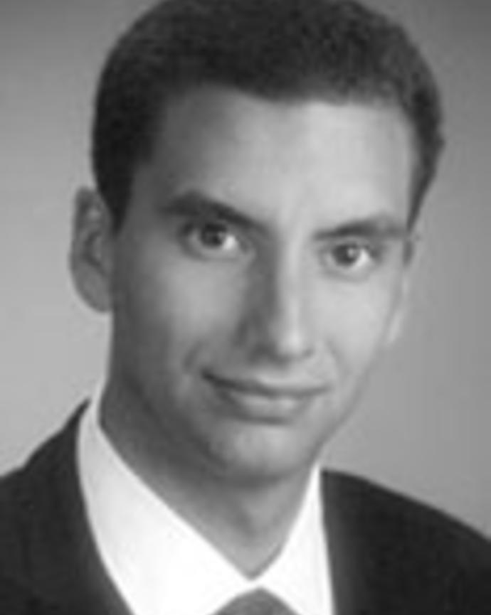 Patrik Johansson is wearing a white shirt, black blazer, and tie. He has cropped dark hair.