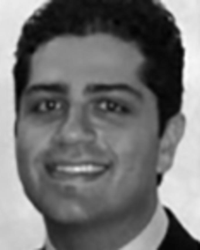 Basram Kasravi has short black hair and is wearing a suit.