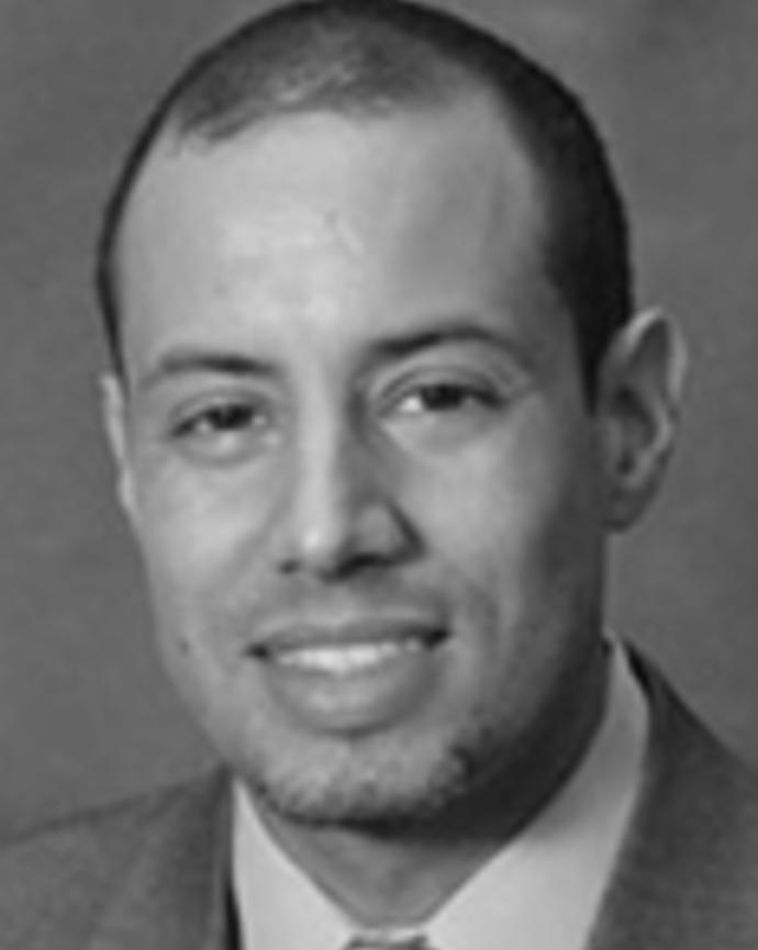 Julian Nieves has very short black hair and light facial hair.