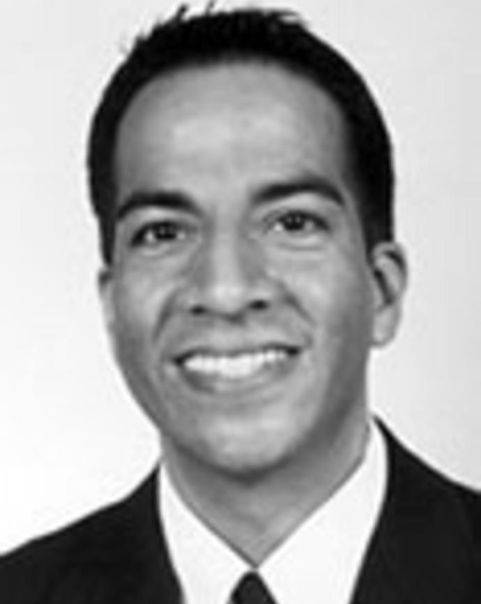 David Nunez has short black hair and is wearing a suit. 