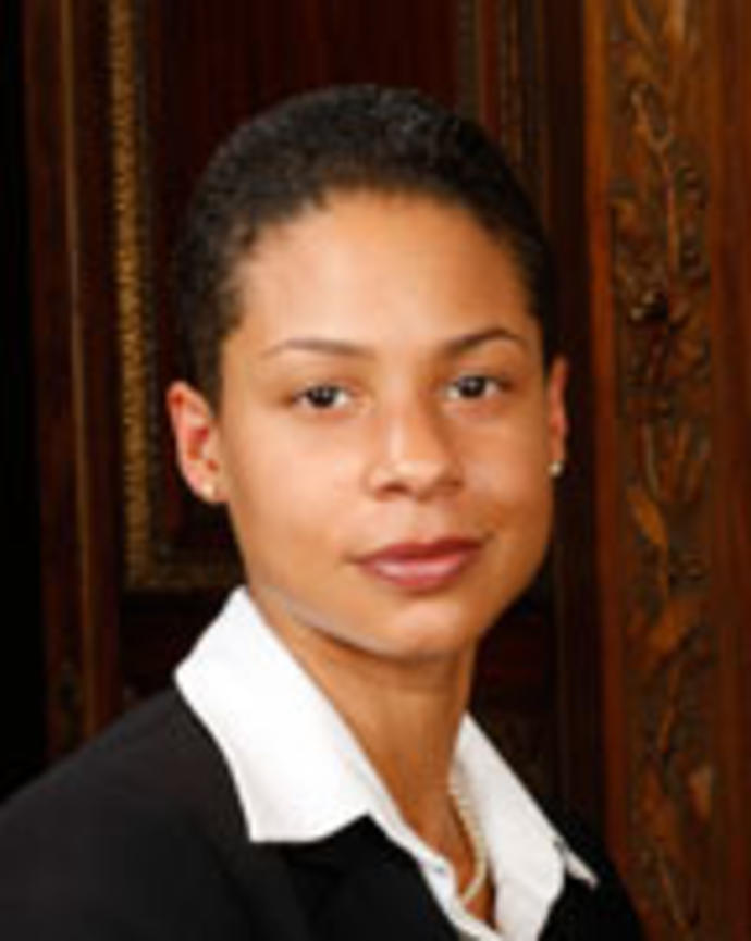 Pamela Rily has short black hair and is wearing a white shirt with a black blazer.