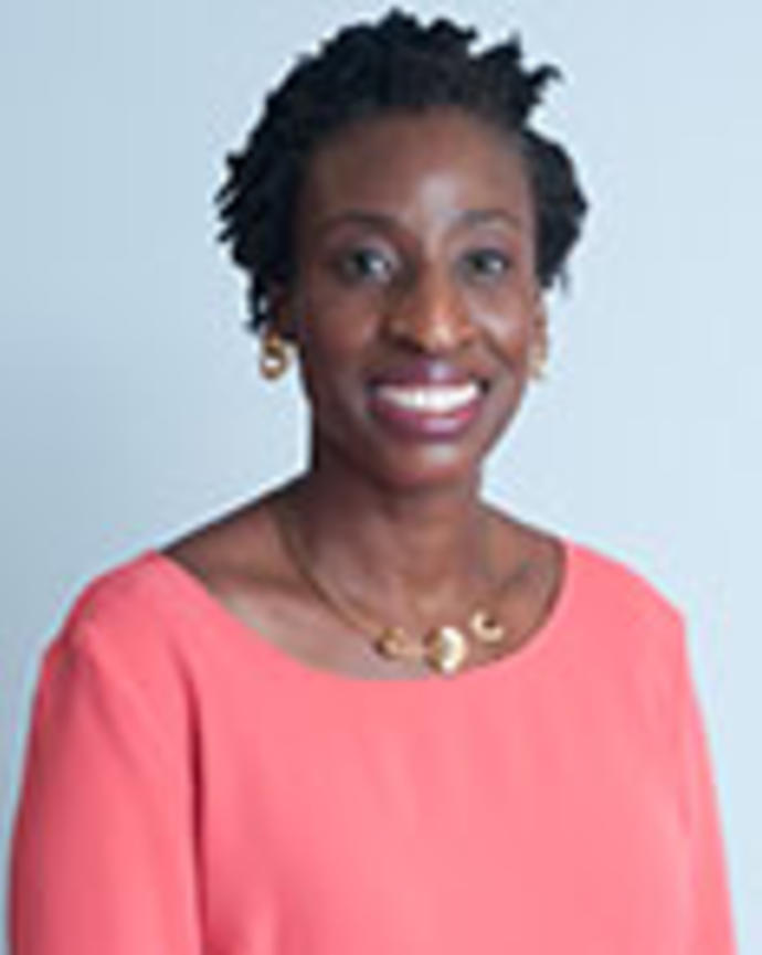 Salewa Oseni has short coily black hair. She is wearing a pink blouse and gold jewelry..