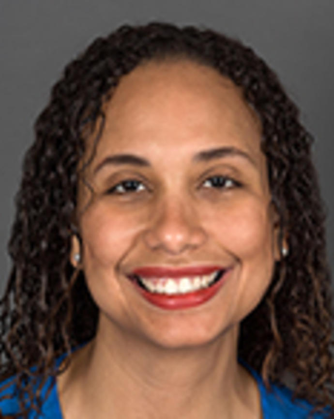 Frinny Polanco has long curly brown hair. She is wearing a blue dress.
