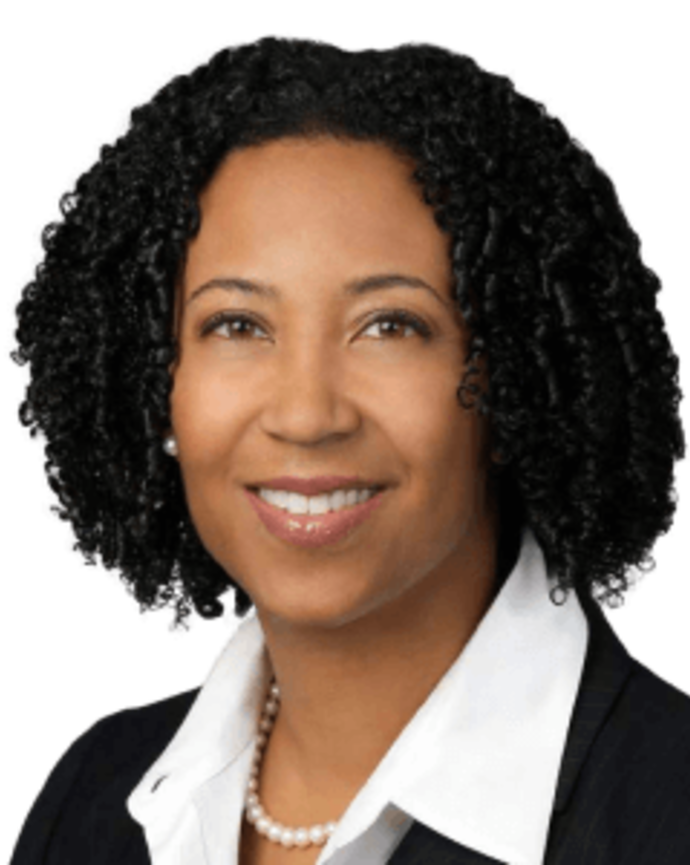 Dora Hughes is wearing a black blazer and white shirt. She has chin-length curly black hair.