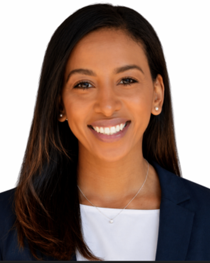 Falen Demsas has long straight black hair. She is wearing a white shirt and black blazer.